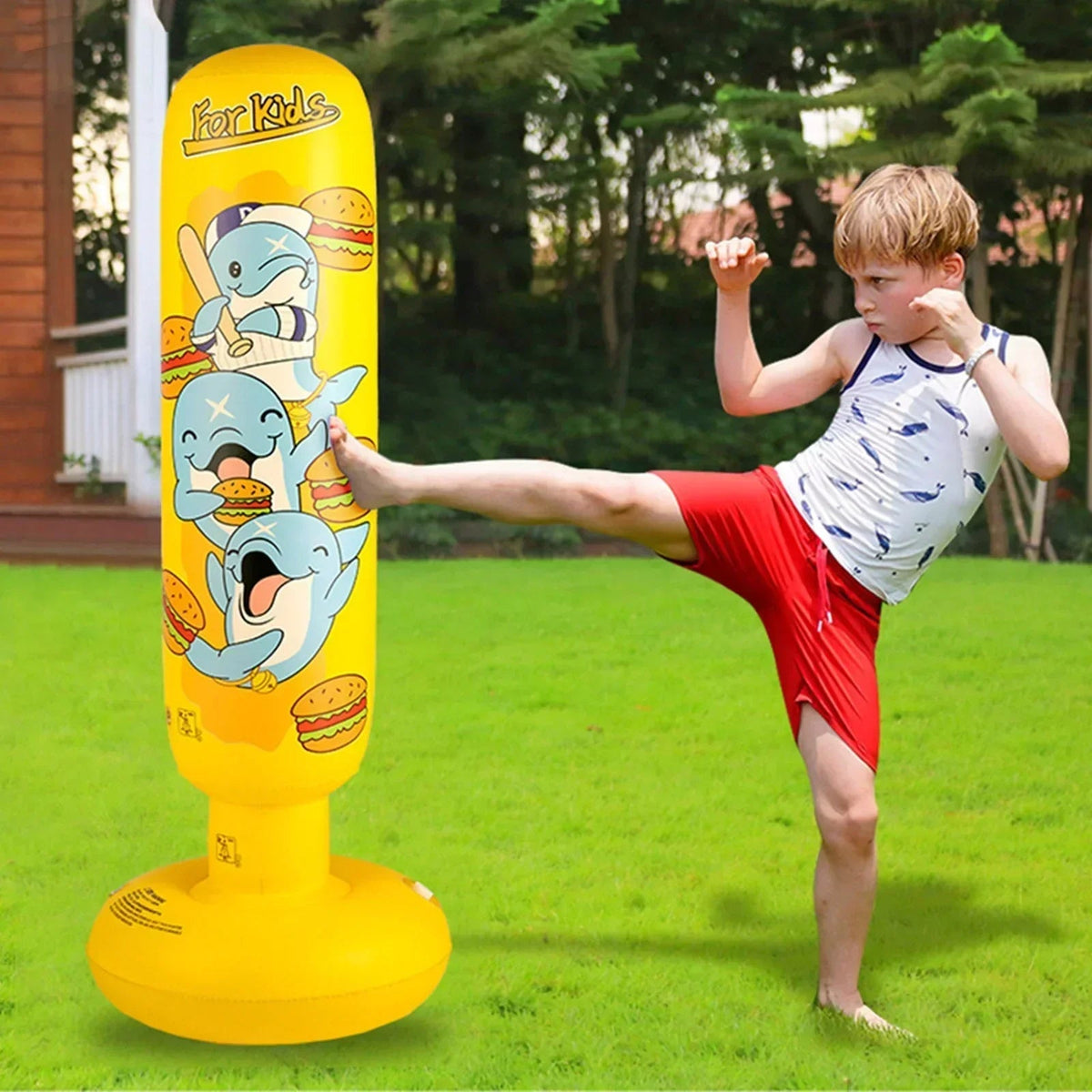 Enfant jouant avec le sac de frappe gonflable jaune dans un jardin